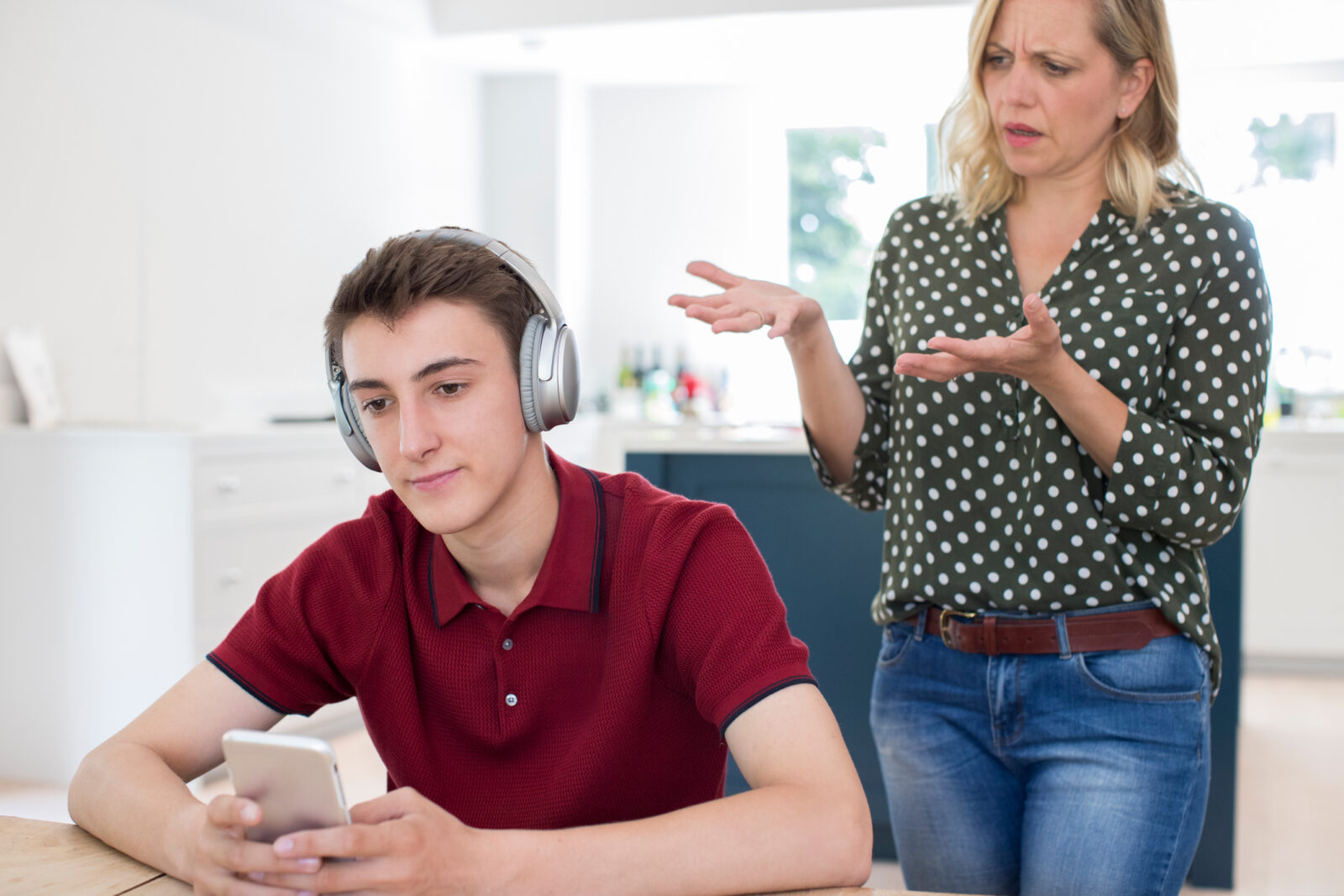 teenage boy listening to headphones on phone ignoring mom